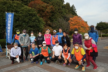 色付いた木々の前で「仙台市視覚障害者ＲＣ」の旗を横にメンバーが前後に並んでいる