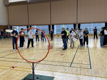 �ւ̒��S��_���ăt���C���O�f�B�X�N�𓊂��Ă���j���Q����